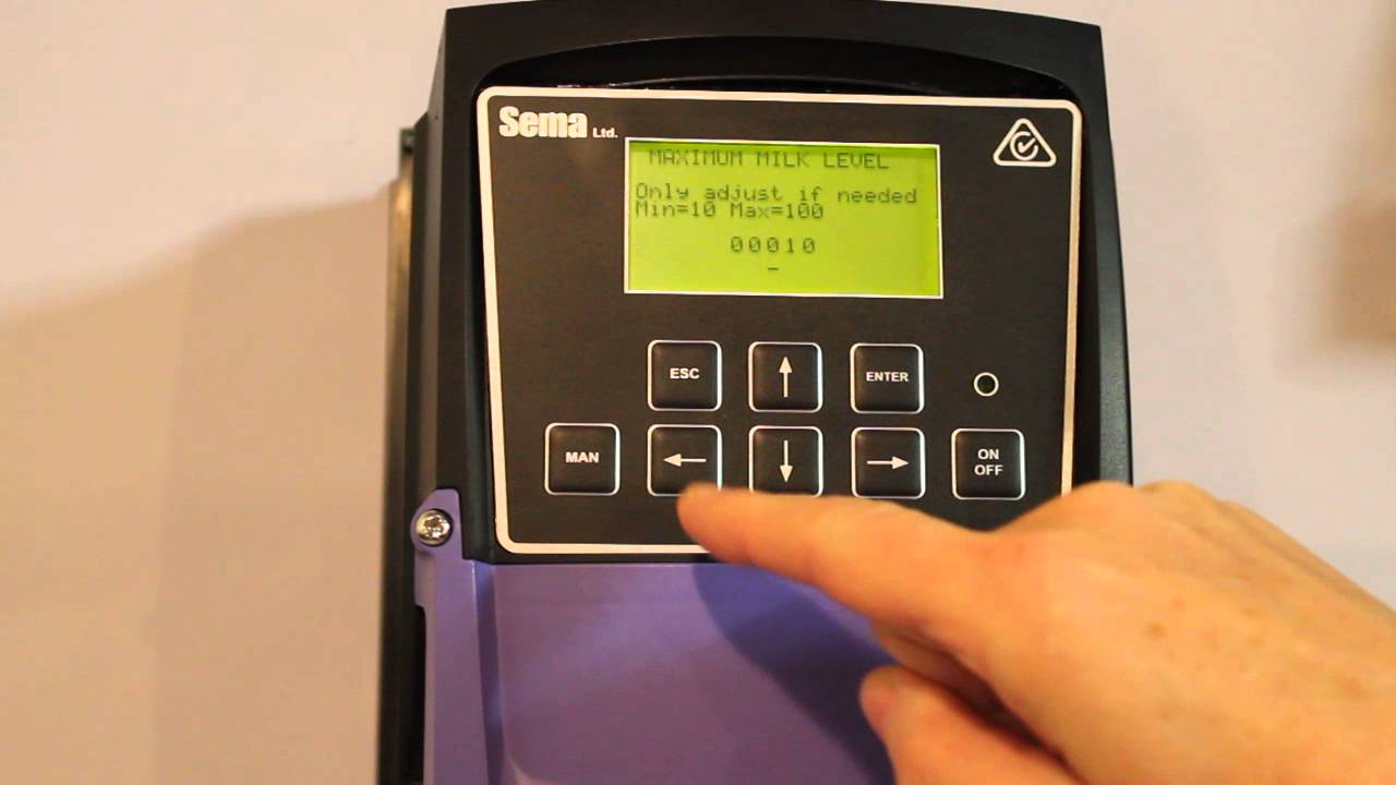 Membrane keypad and LCD control panel on a Sema dairy metering unit, with a finger pressing a tactile button